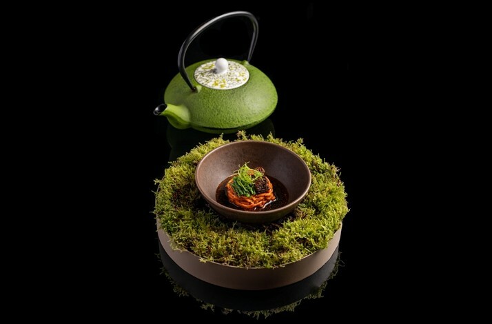 A green teapot featuring a bowl with a dish.