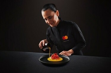 The chef wearing the uniform with the branded MC logo in the process of preparing the dish.