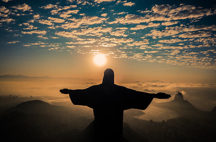 Christ the Redeemer statue silhouetted against a sunrise sky. 