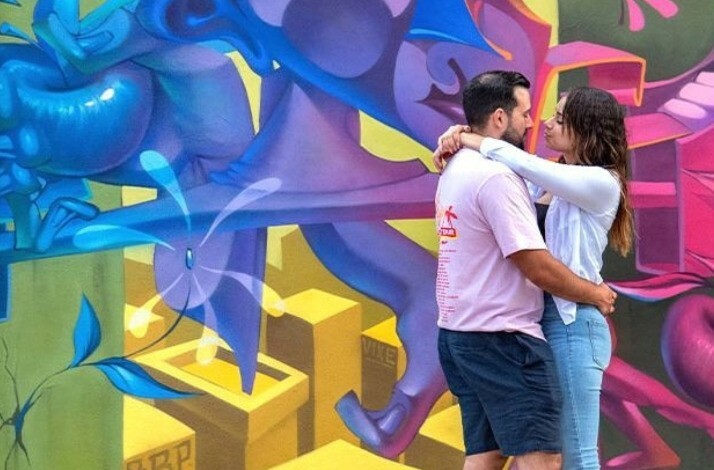 A couple hugging each other with a graffiti wall on the background at Wynwood Walls Museum.