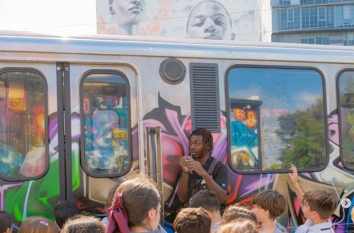 A man standing next to the train with a graffiti on it.
