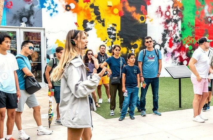 A woman guide telling people about the outdoor mural gallery and street art museum Wynwood Walls.