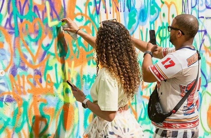 A man and a woman drawing graffiti on the wall at Wynwood Walls Museum.