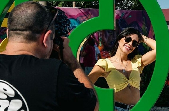A man taking a picture of a woman standing next to art installation at Wynwood Walls Museum.