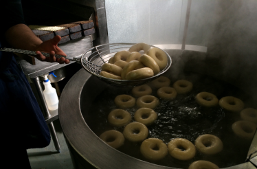 A baker is boiling a batch of bagels at Russ & Daughters. 