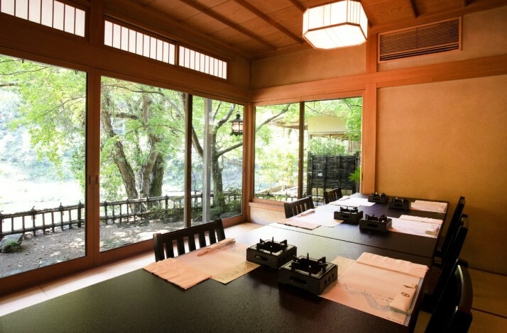 Traditional Japanese dining room with large windows overlooking a garden.